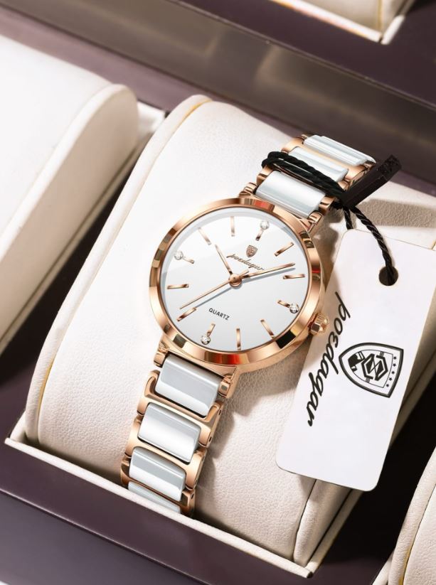Watch with white strap and rose gold casing on a beige cushion, brand tag visible
