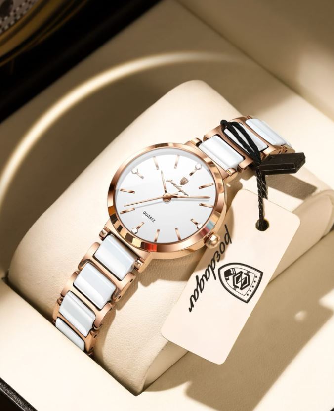 Luxury watch with white ceramic strap and rose gold casing on a beige cushion, brand tag visible.